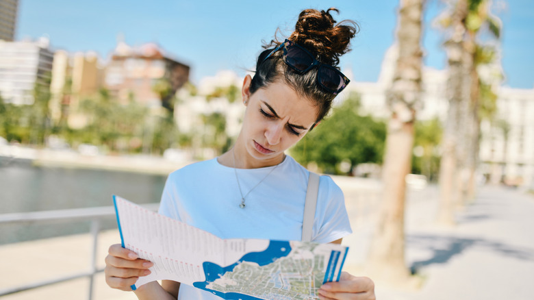 Female tourist reading a city's map looking lost and confused