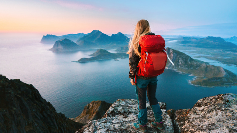 Woman mountaineering with backpack in Lofoten islands enjoying aerial view.
