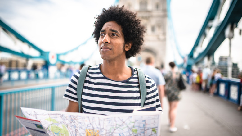 Solo traveler at tower bridge area holding a map.