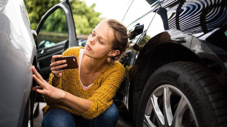 woman taking pictures of rental car damage