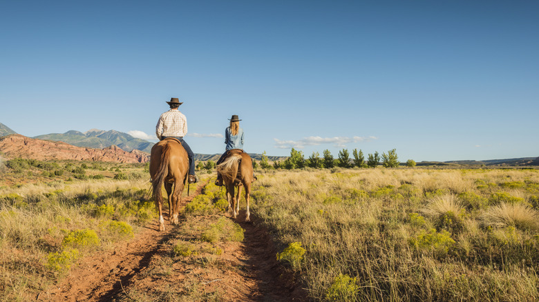 Two people ride horses on a ranch