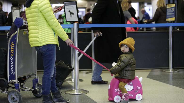 child sitting on luggage in airport