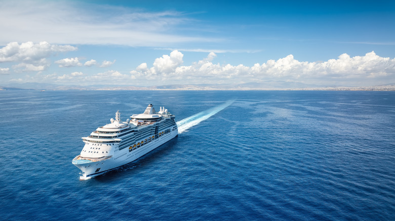 Aerial front view of a cruise ship sailing with speed over the calm ocean.