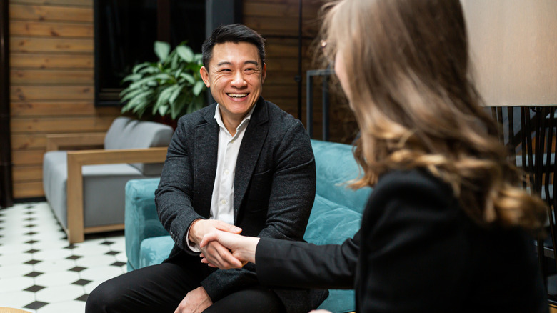 two people shaking hands on couch