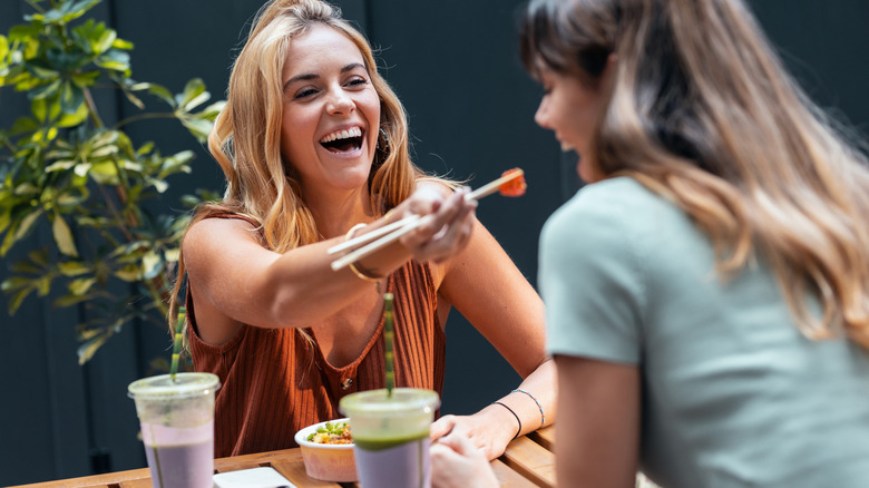 two women eating with chopsticks