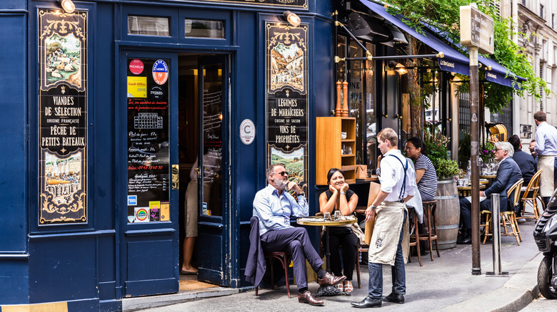 a couple sitting talking to the waiter at a French restaurant