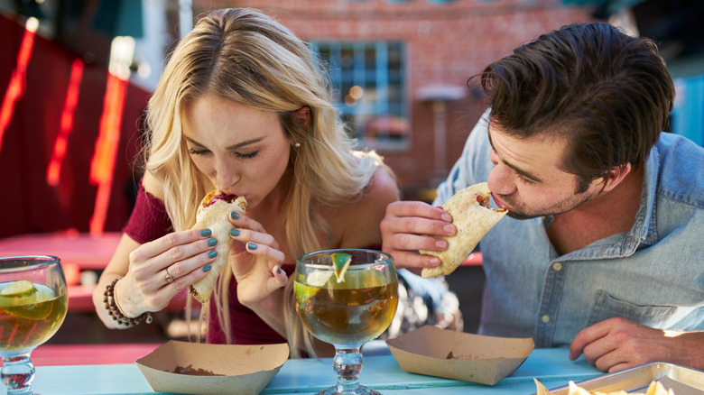 Two American tourists eating tacos.
