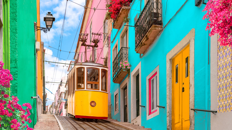 Yellow typical tram on a street with colorful houses and flowers on the balconies