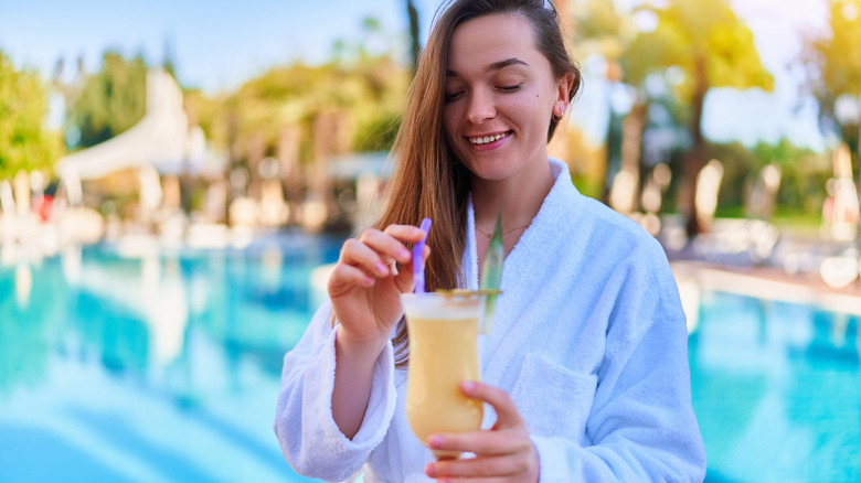 woman enjoying tropical drink at pool