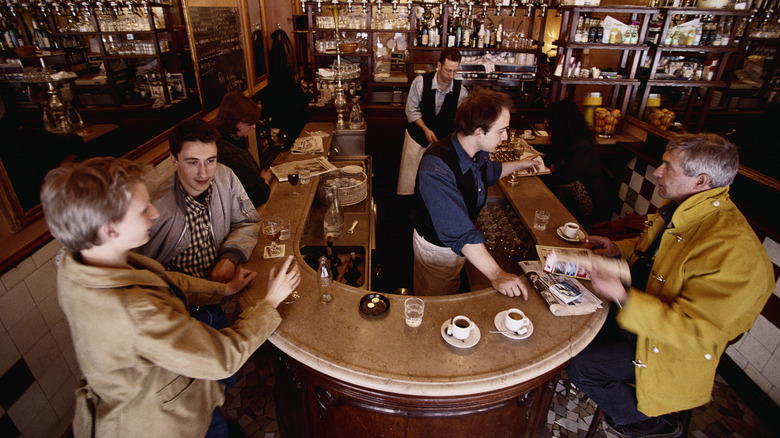 People standing around a counter drinking coffee in France