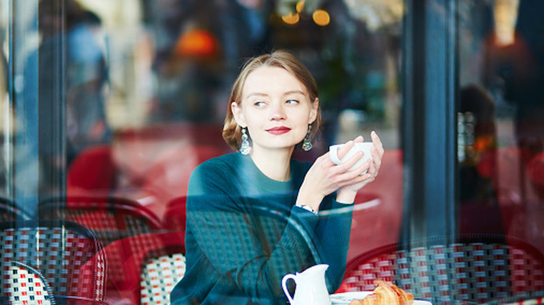 A young woman drinking coffee sitting in a cafe in Paris