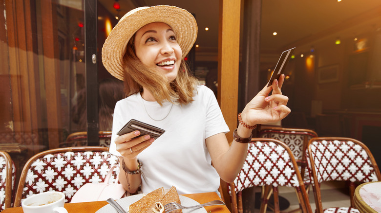 A woman holding out a credit card in Paris