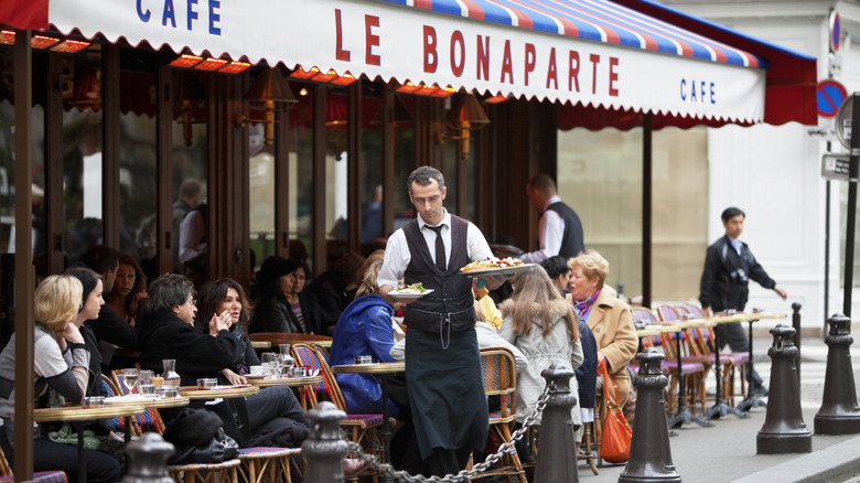 A waiter serves food outdoors at a restaurant in Paris