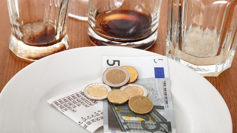 Some coins and paper euros with a receipt on a plate