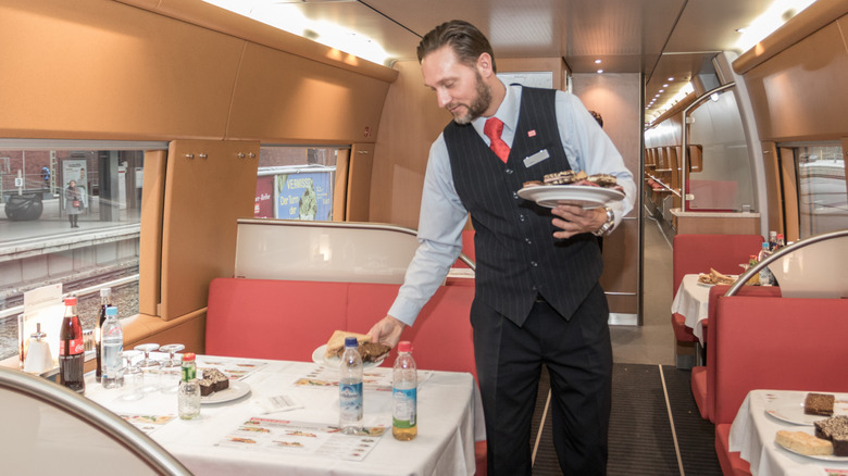 Waiter clearing a table in a train dining car