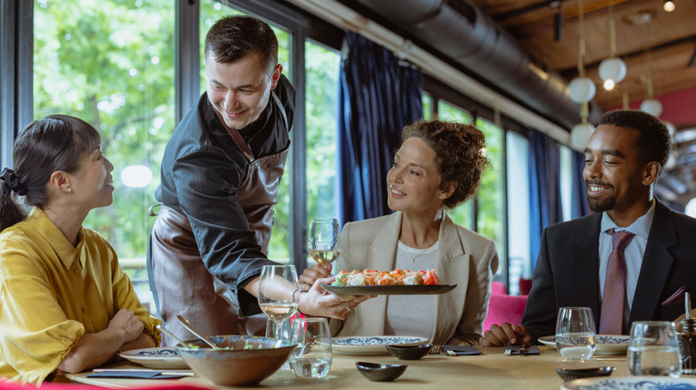 A waiter serving a meal to a group of business people in a restaurant.