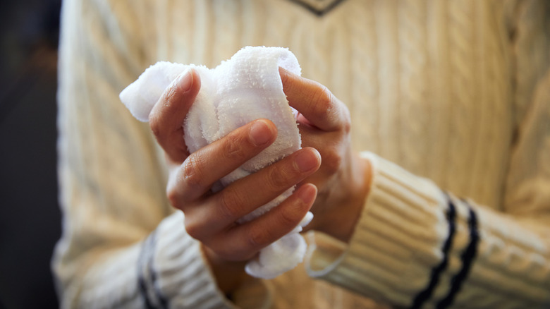 Close-up of hands washing with a wet towel.