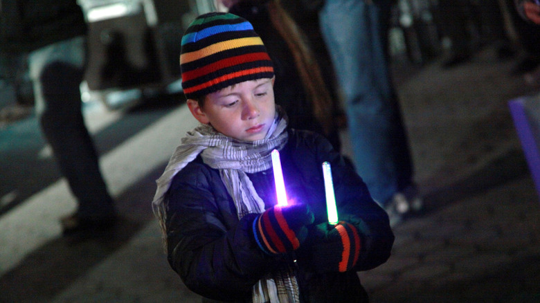 Small kid holding two glow sticks