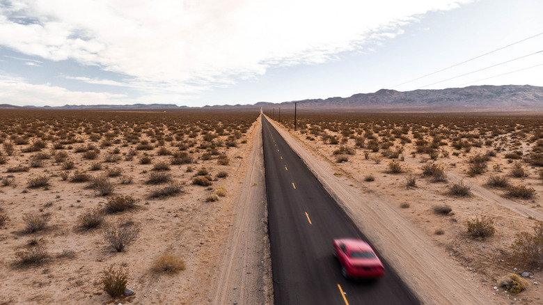 A red car speeds through the desert