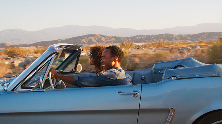 Two people behind the wheel of a convertible