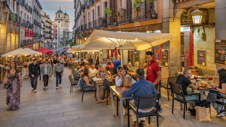 Diners sitting at tables on a street outside a restaurant in Spain.