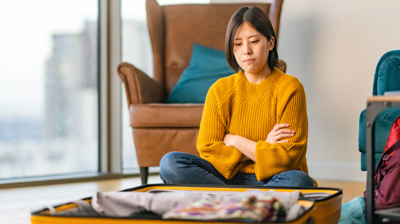 Woman upset sitting in front of open suitcase