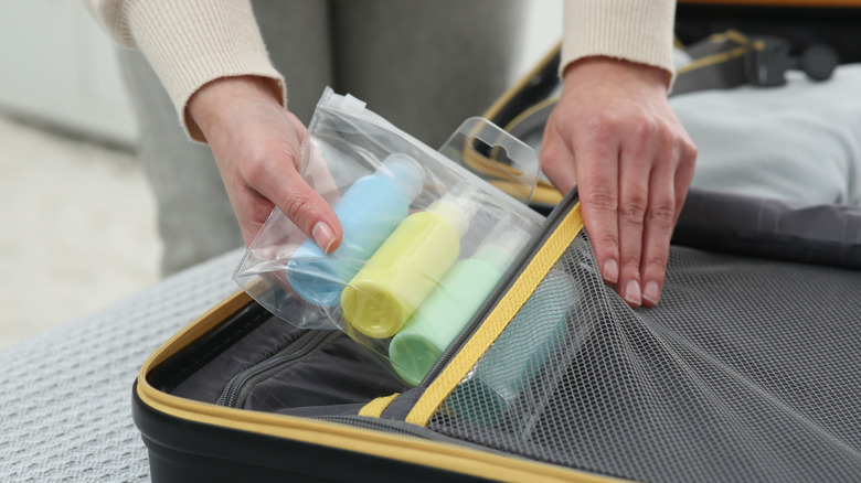 A person packing a plastic bag full of liquids.