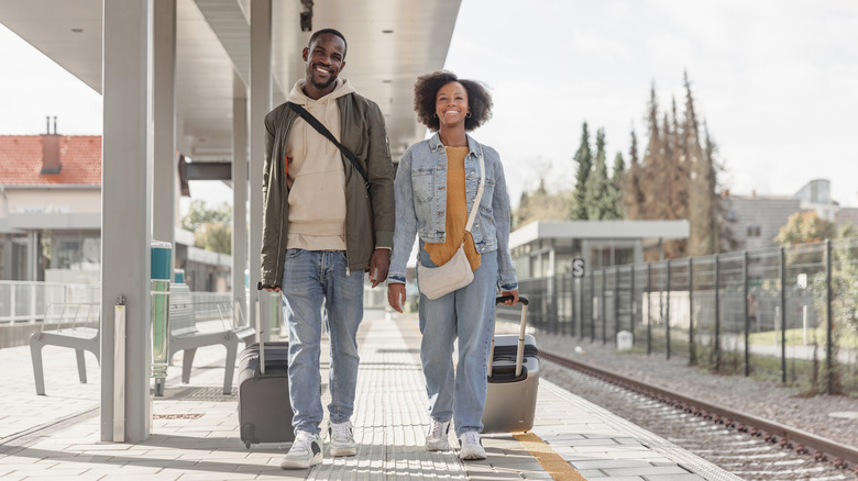 a man and woman walking along the platform at a train station in Europe