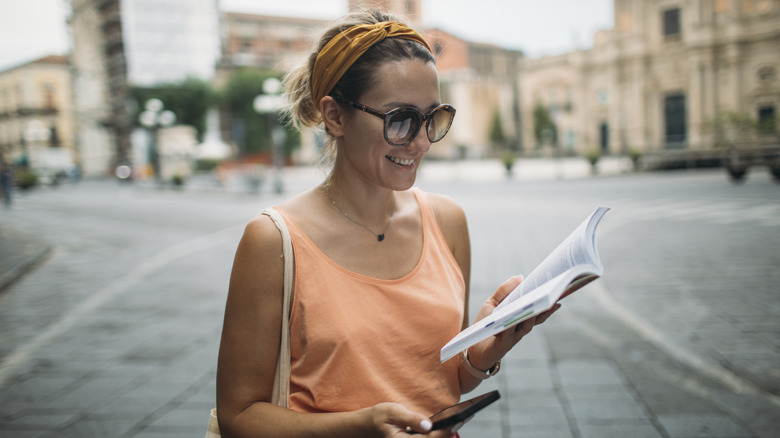 a young woman using a guide book and navigation app