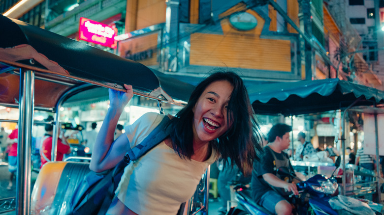A smiling traveler on a tuk-tuk in Thailand.