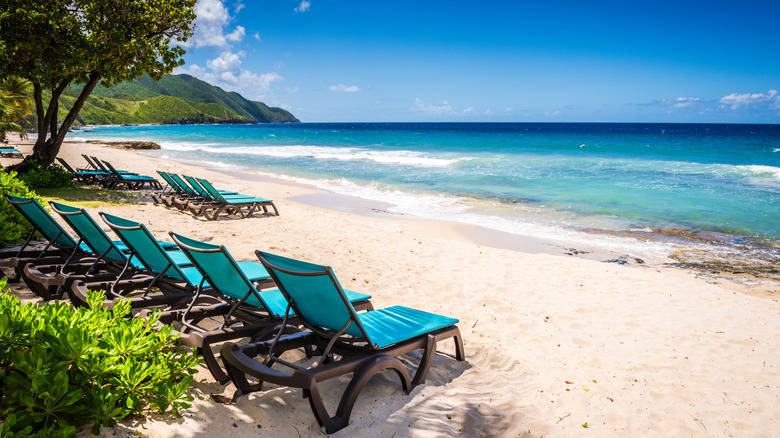 Teal fabric lounge chairs line white sand beach on St Croix