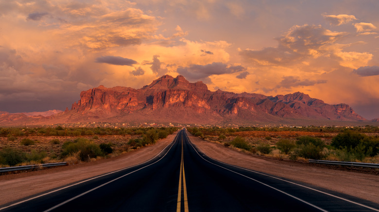 Long, straight road to the Superstition Mountains in Arizona at sunset