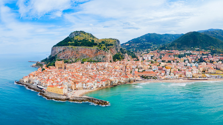 Panoramic view of white medieval houses of Cefalu city above the golden-sand beach