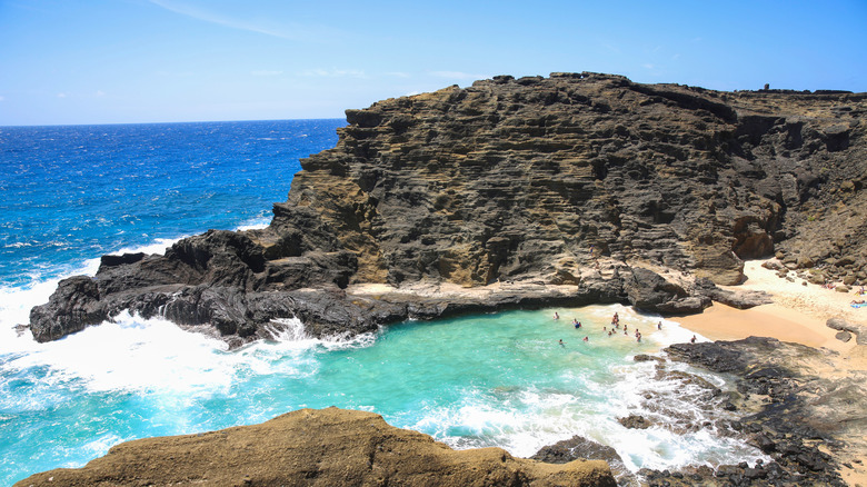 Rocks and ocean surround a tiny golden-sand beach