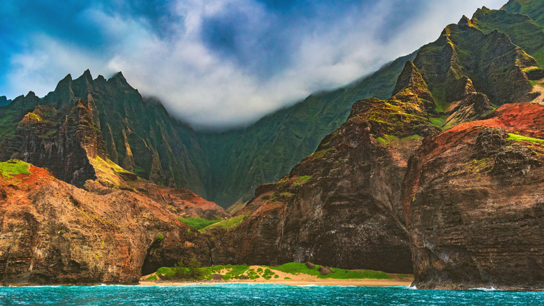 Jagged cliffs and mountain peaks back a tiny sandy beach