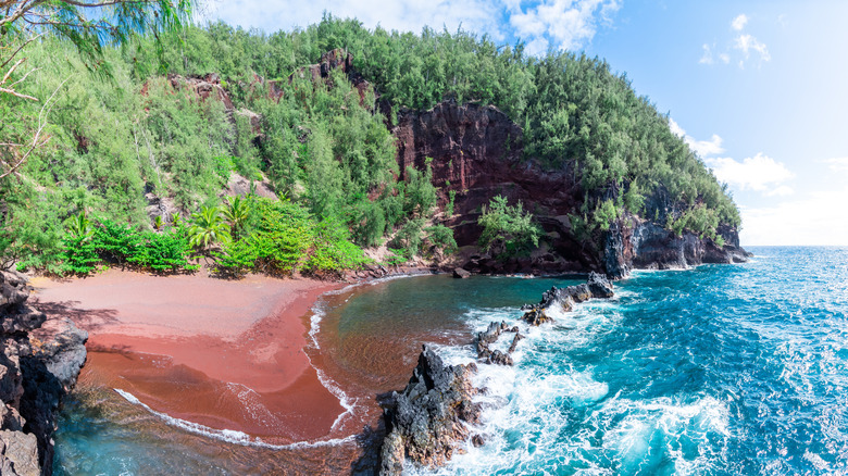 Red sand and turquoise water in a lagoon backed by forests