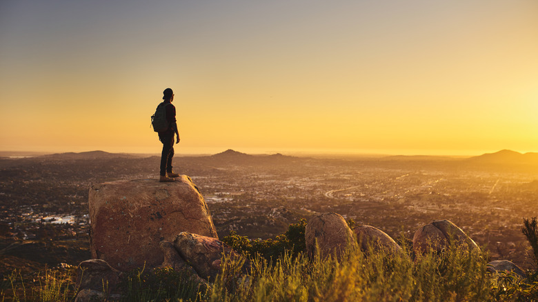Hiker on a rock overlooking San Diego at sunset