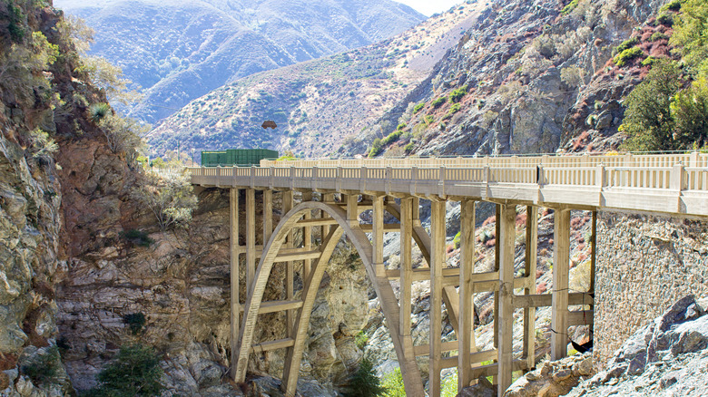 Arch bridge over canyon with mountain backdrop