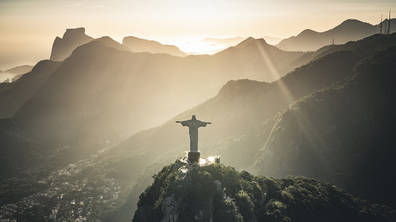 Aerial view of Christ the Redeemer and the Rio de Janeiro skyline with golden light shining all around it