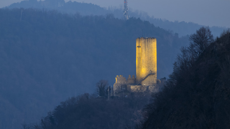 A winter landscape shows the lit-up tower of Castello Baradello in Northern Italy
