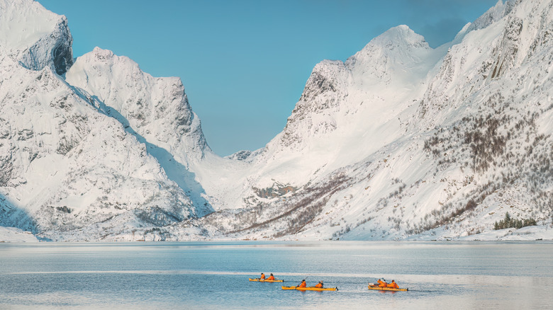 Yellow kayaks floating with snow-covered mountains in the background