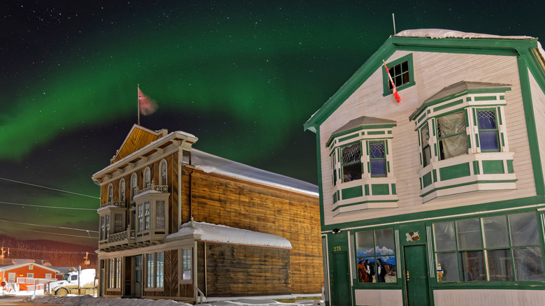 Aurora over wooden buildings in snowy landscape