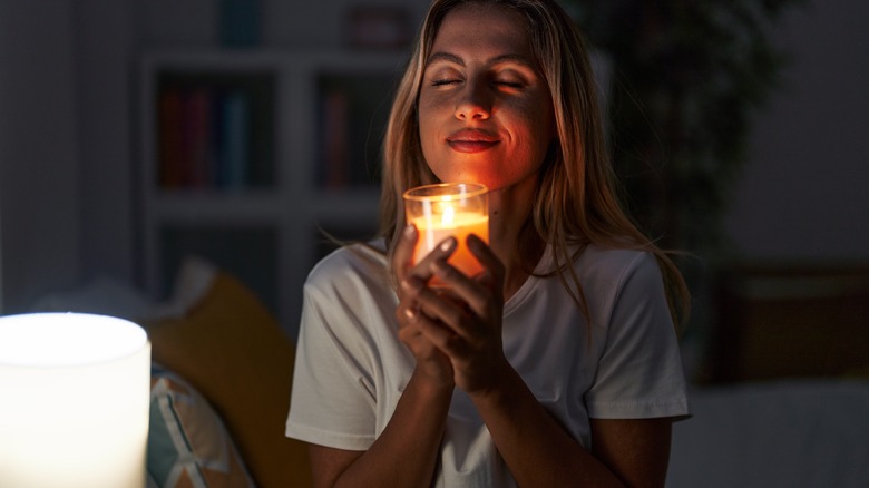 Smiling woman smelling lit candle