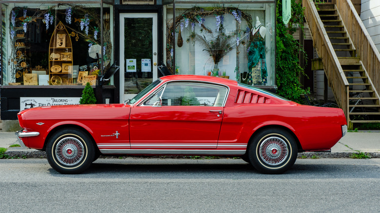 A vintage red Mustang sits in front of a quaint shop in Phoenicia, New York