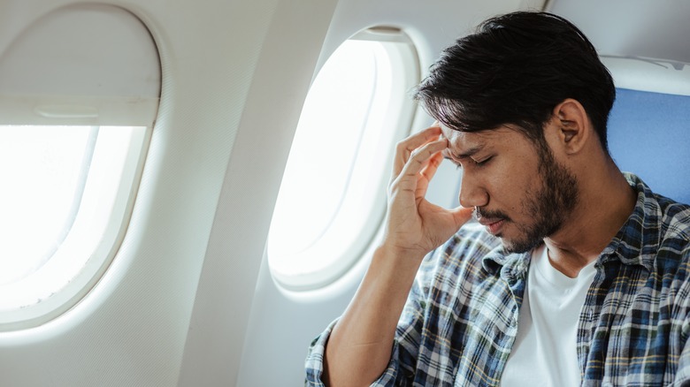 Man on plane holding head