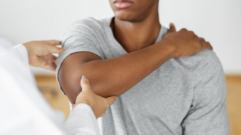 Doctor checking patient's elbow