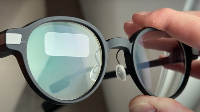 someone holding a pair of black rimmed round smart glasses