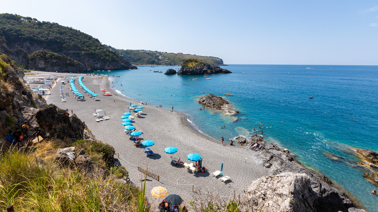 a wide beach with clear water and sun umbrellas