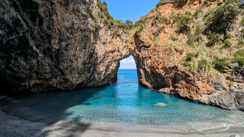 a secluded beach framed by a huge rocky arch