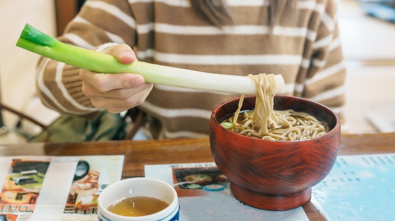 Woman enjoys bowl of negi soba